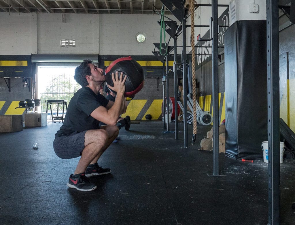 Man squatting down about to throw a wall ball