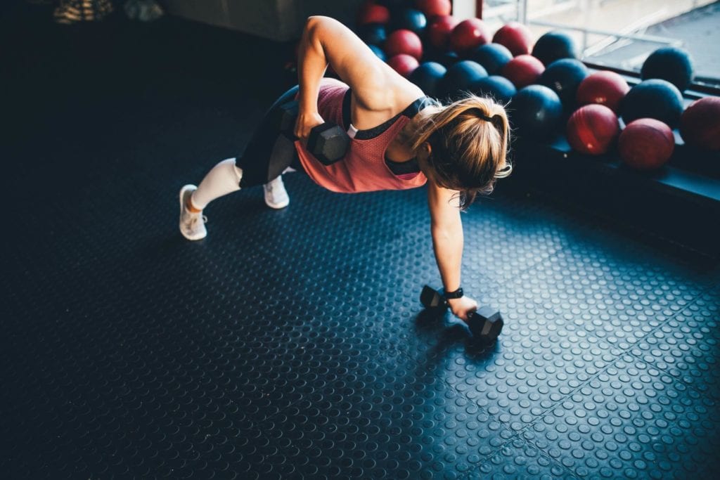 Woman in a gym doing renegade rows with dumbbells